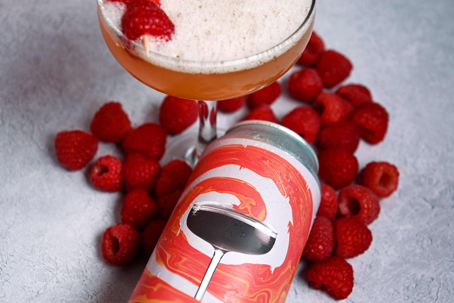 Northern Spirits French Martini Pale Ale can with raspberries and cocktail glass on a textured surface.