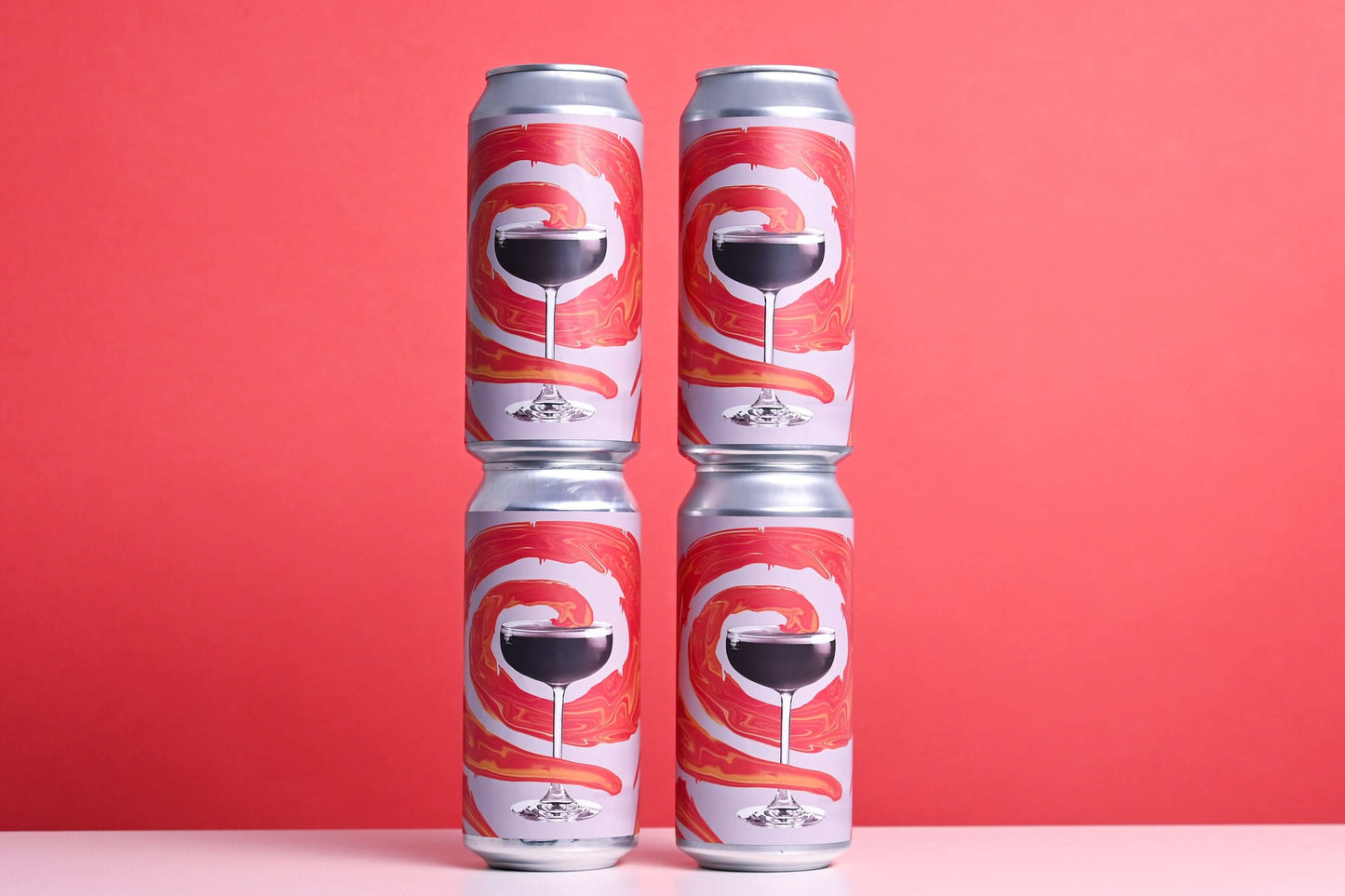 Four-pack of Northern Spirits French Martini Pale Ale cans with red swirl design against a red background.