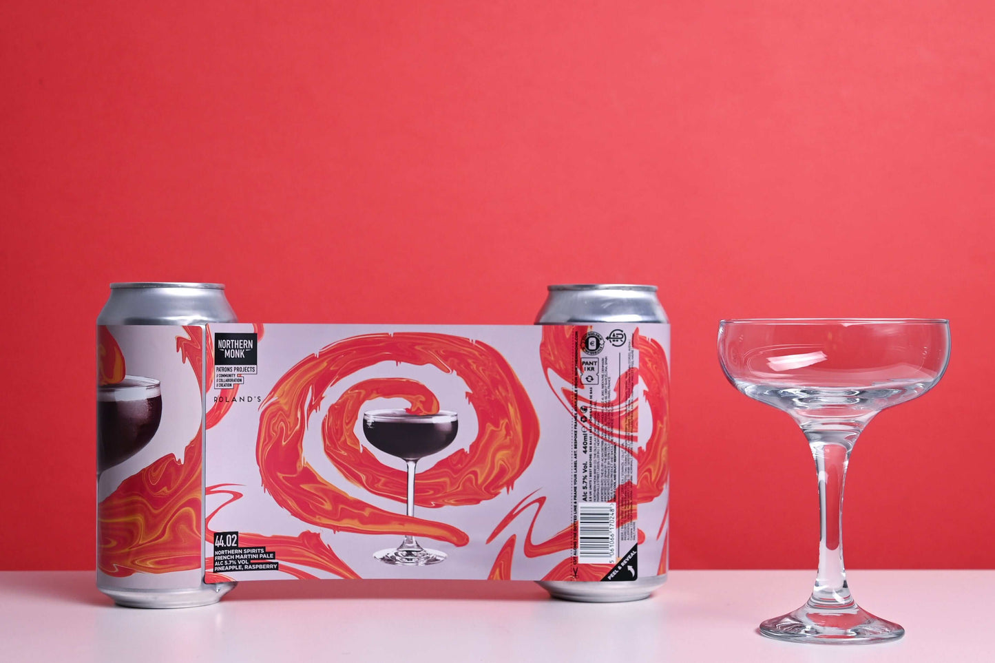 4-pack Northern Spirits French Martini Pale Ale cans with cocktail glass against red background.