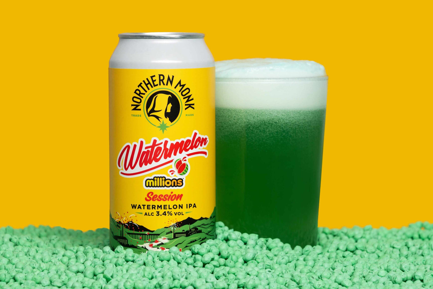 Northern Monk Watermelon Millions Session IPA can and glass on green sweets against yellow background.